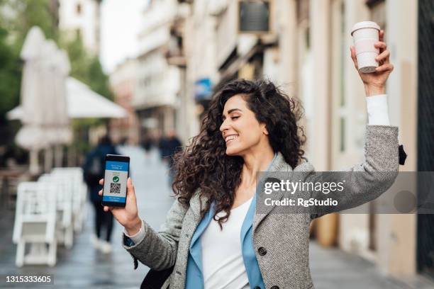 woman showing her digital vaccine passport on the phone cheering and dancing on the street - dancing studio shot stock pictures, royalty-free photos & images