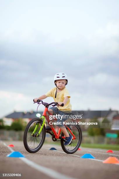 boy in a helmet (4-5 years old) standing on a bicycle in a park-stock photo - 4 5 years stock-fotos und bilder