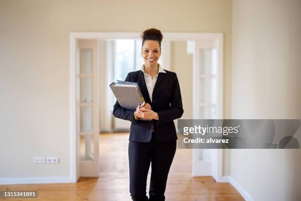 portrait of smiling saleswoman with file at home - real estate agent stock pictures, royalty-free photos & images