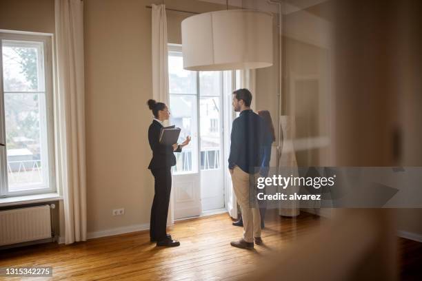 makelaar die huis verkoopt aan een jong paar - huizenmarkt stockfoto's en -beelden