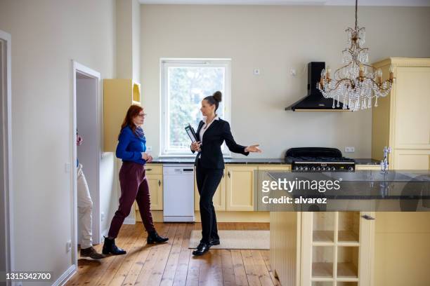 pareja entrando mientras agente de bienes raíces muestra nueva cocina - flat inspection fotografías e imágenes de stock
