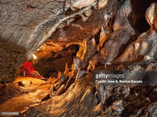 seated caver resting inside a large underground cave. - potholing stock pictures, royalty-free photos & images