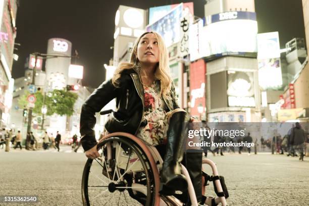 portrait of asian woman has a wheelchair solo travel in the night - reclamebord activiteit stockfoto's en -beelden