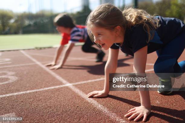 young girl and boy ready to race on an athletics track - leichtathlet stock-fotos und bilder