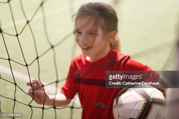 A young girl posing with a ball on a soccer field