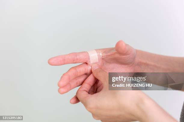 female putting adhesive bandages plaster for first aid. - hand laceration - fotografias e filmes do acervo