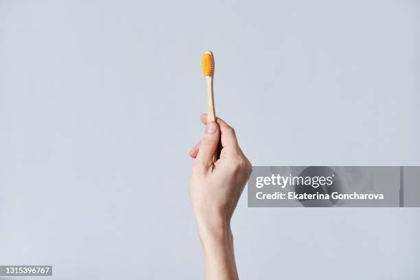 a toothbrush made of natural bamboo material in a woman's hand on a white isolate background. - bambù materiale foto e immagini stock