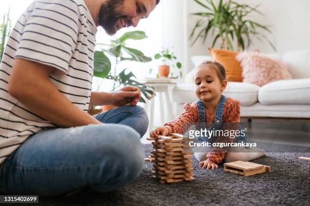 young father and little daughter playing jenga in living room - jenga stock pictures, royalty-free photos & images