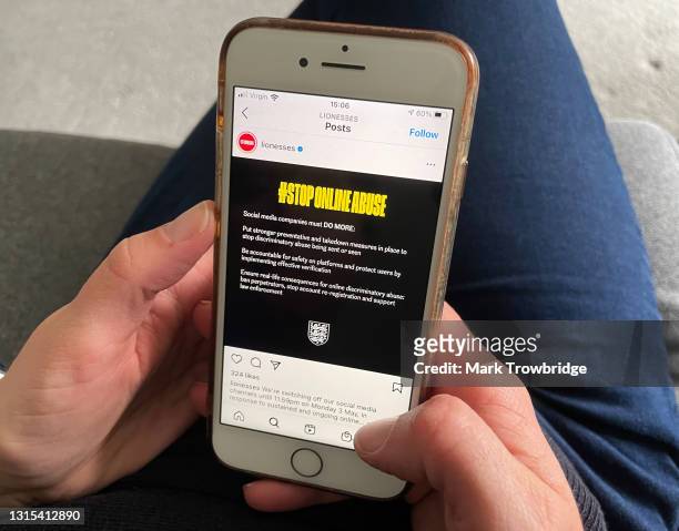 In this photo illustration, the photographer's wife looks at an England Lionesses Instagram post protesting against online abuse on April 30, 2021 in...
