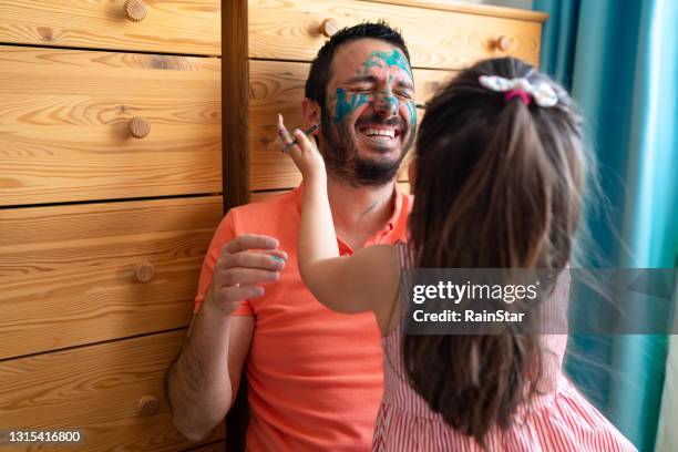 the father, whose face is painted by his little daughter, has quite fun - face painting imagens e fotografias de stock