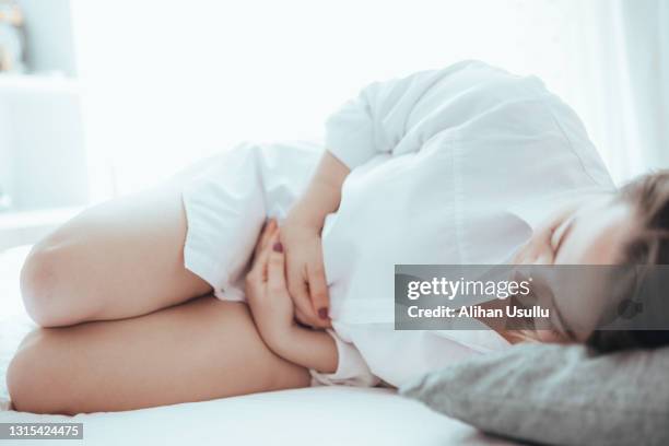 junge frau, die unter menstruationsschmerzen leidet, hält ihren bauch - harnwegsinfektion stock-fotos und bilder