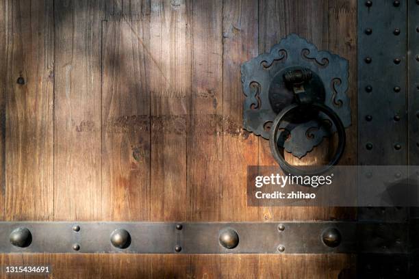 the metal knocker on the wooden door has a sunlight effect - prego - fotografias e filmes do acervo