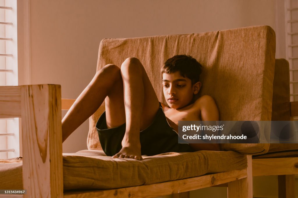 Young boy playing game on mobile phone at home