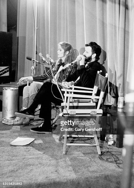 View of American actress Barbara Bach and British musician Ringo Starr as they sit in directors chairs, both with cigarettes, during a taping of the...