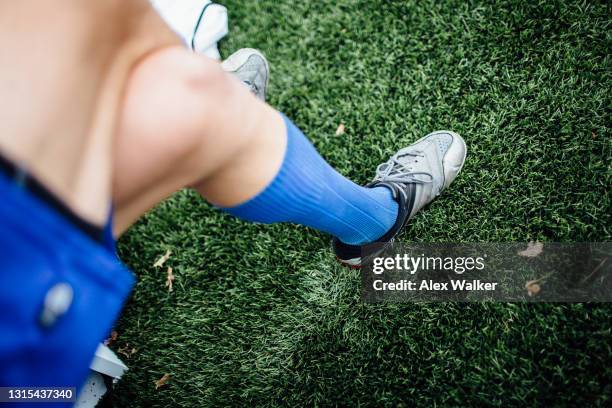 low section of a football player with long blue socks and training shoes on grass - schuhe frau von oben stock-fotos und bilder