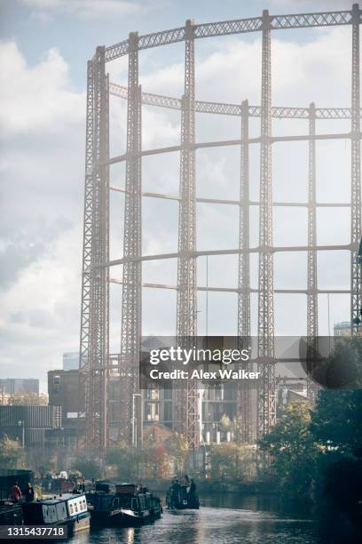 gas holder frames and regent's canal with narrowboats - gasometro foto e immagini stock