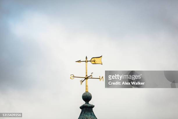 gold weathervane against cloudy sky - spire stock pictures, royalty-free photos & images