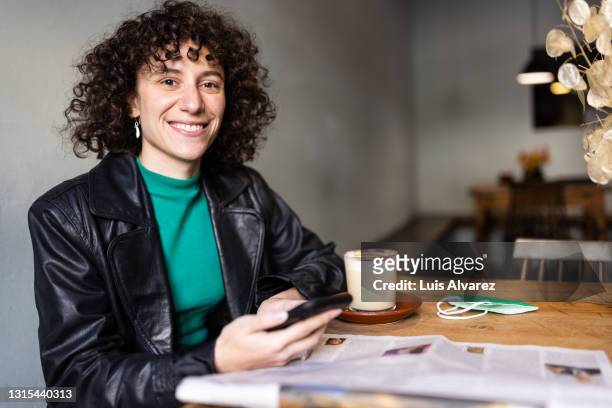 portrait of a happy non-binary person sitting in a coffee shop - accessibilità foto e immagini stock