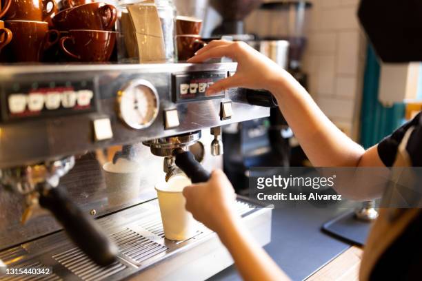 barista making a coffee using a steaming hot coffee machine in a bakery - cafeteria imagens e fotografias de stock