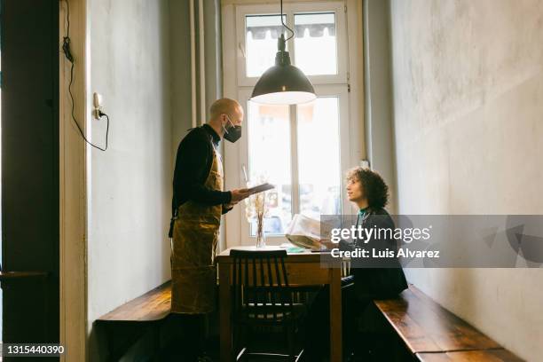 waiter attending a non-binary customer in a vintage restaurant - vintage restaurant ストックフォトと画像