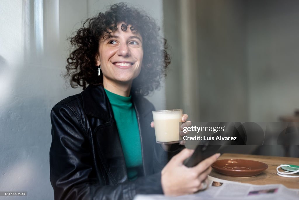 Non-binary person day dreaming while reading a text message on the phone