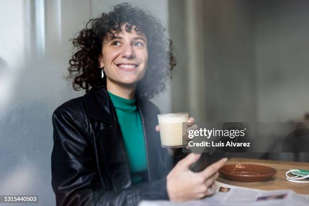 non-binary person day dreaming while reading a text message on the phone - örhänge bildbanksfoton och bilder