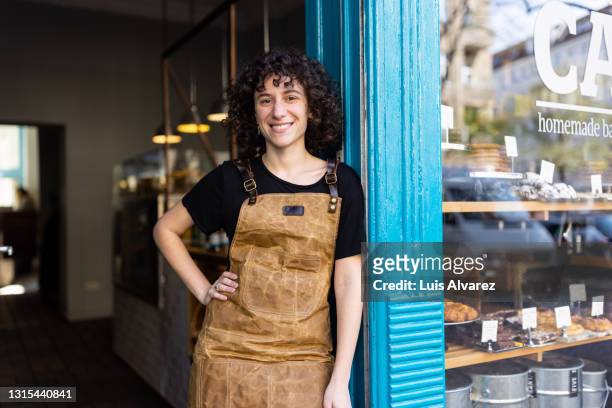 portrait of a non-binary person owner standing in from of their small bakery - new business stock-fotos und bilder