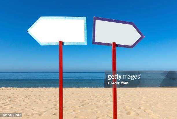 two arrow signs on the beach - links platz stock-fotos und bilder