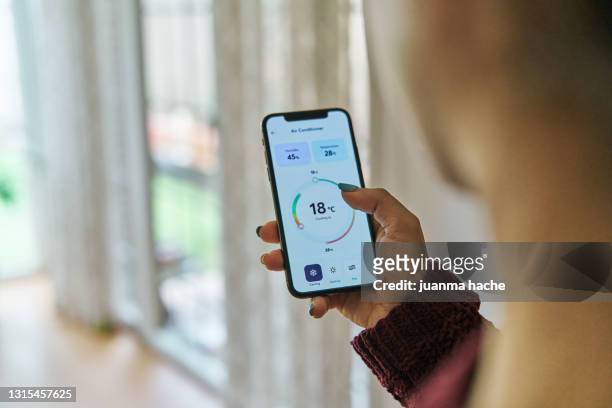 woman controlling the smart room temperature from a smartphone app - control room monitors stockfoto's en -beelden