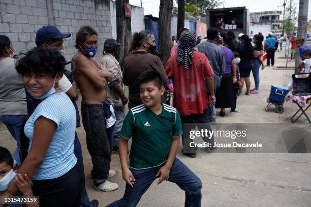 Children smile as residents line up in the community of "La Verbena", zone 7 of the city, to receive a plate of food given by the government on April...