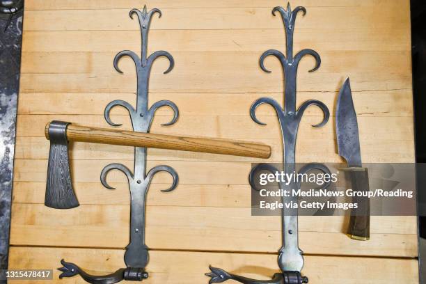 Finished pieces made by Dave Fisher, owner of Fisher Forge, are pictured inside his business. Pictured is a tomahawk, Maravian hinges, and a bowie...