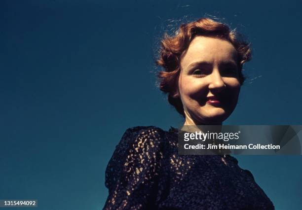35mm film photo shows a waist-level portrait of the photographer's wife. She wears a navy-colored blouse and smiles against the backdrop of a bright...