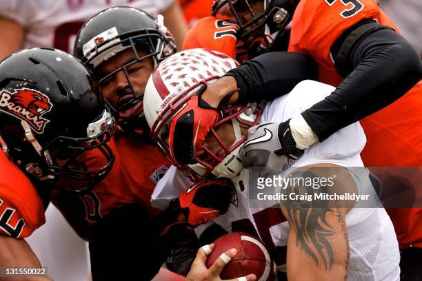 Running back Tyler Gaffney of the Stanford Cardinal is brought down by cornerback Jordan Poyer, safety Lance Mitchell and safety Anthony Watkins of...