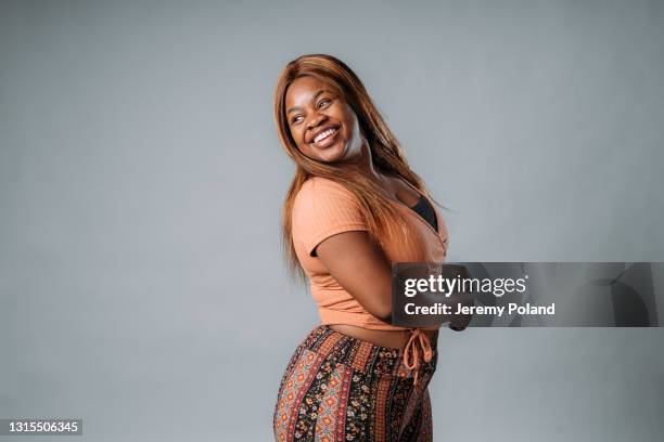 retrato de una joven afroamericana hermosa, segura y de moda riendo en un fondo de estudio gris - black teenage models fotografías e imágenes de stock