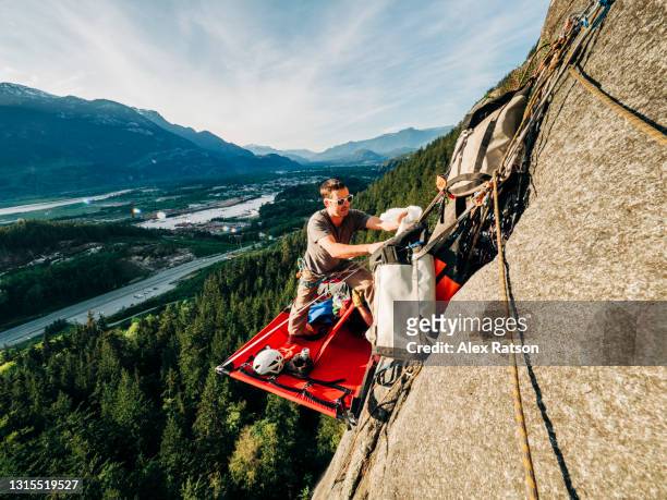 a climber stands on a portaledge high above the ground in squamish, bc - camp site stock-fotos und bilder