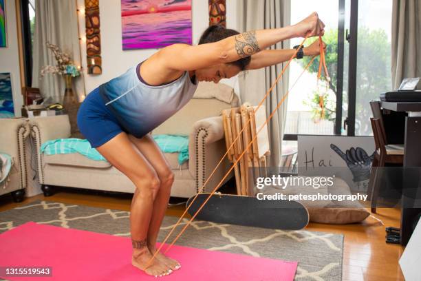 geschikte vrouw die met weerstandsbanden in haar woonkamer uitwerkt - elastiekje stockfoto's en -beelden