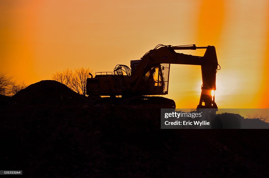 Digger silhouetted against  colour of Sunset