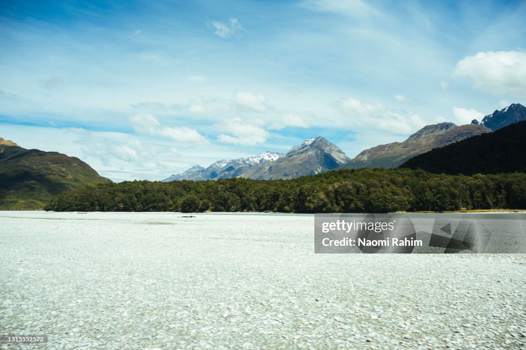 Gravel riverbed of Dart River, surrounded by forested mountains, New Zealand