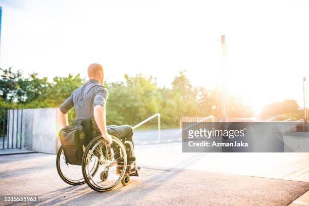 businessman with physical disability rolling into sunshine - man wheel chair stock pictures, royalty-free photos & images