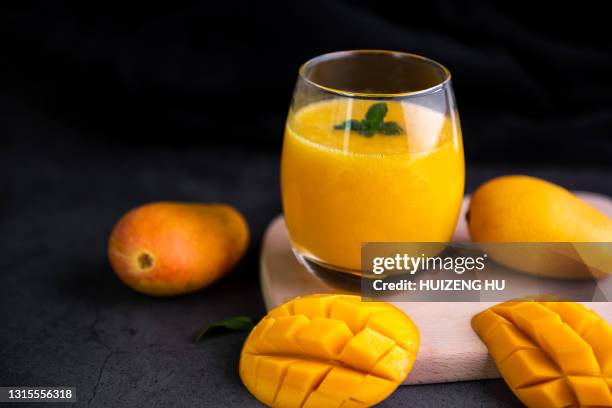 fresh tropical fruit smoothie mango juice on wooden background - mango piece stock-fotos und bilder