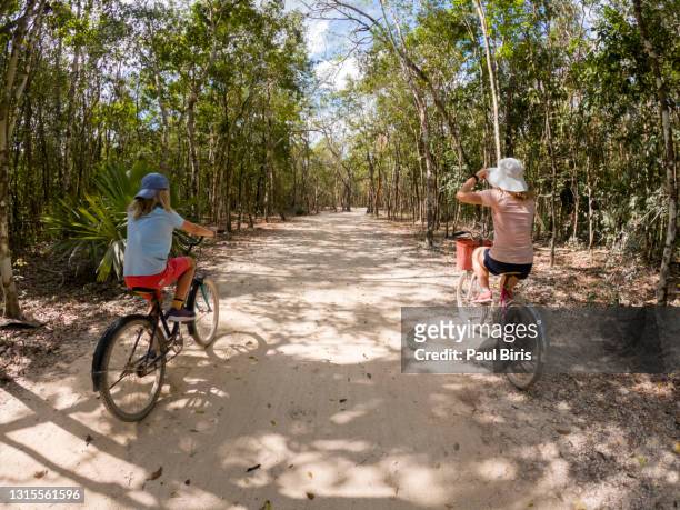 mother and son cycling near the  archaeological aerea in coba, mexico - coba stock-fotos und bilder