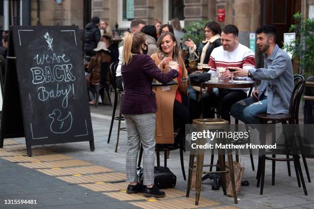 Customers are served while sat at tables outdoors on High Street on April 30, 2021 in Cardiff, Wales. Outdoor hospitality reopened on Monday in Wales...