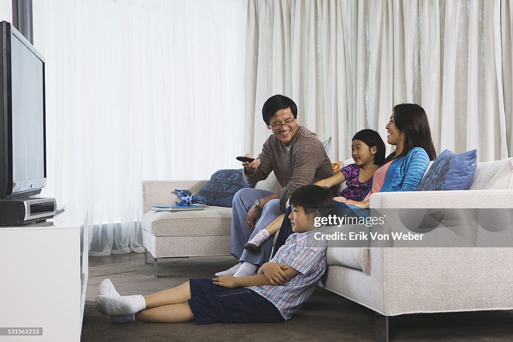 Asian family watching tv in their home