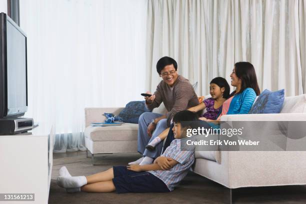 asian family watching tv in their home - asian watching tv stock pictures, royalty-free photos & images