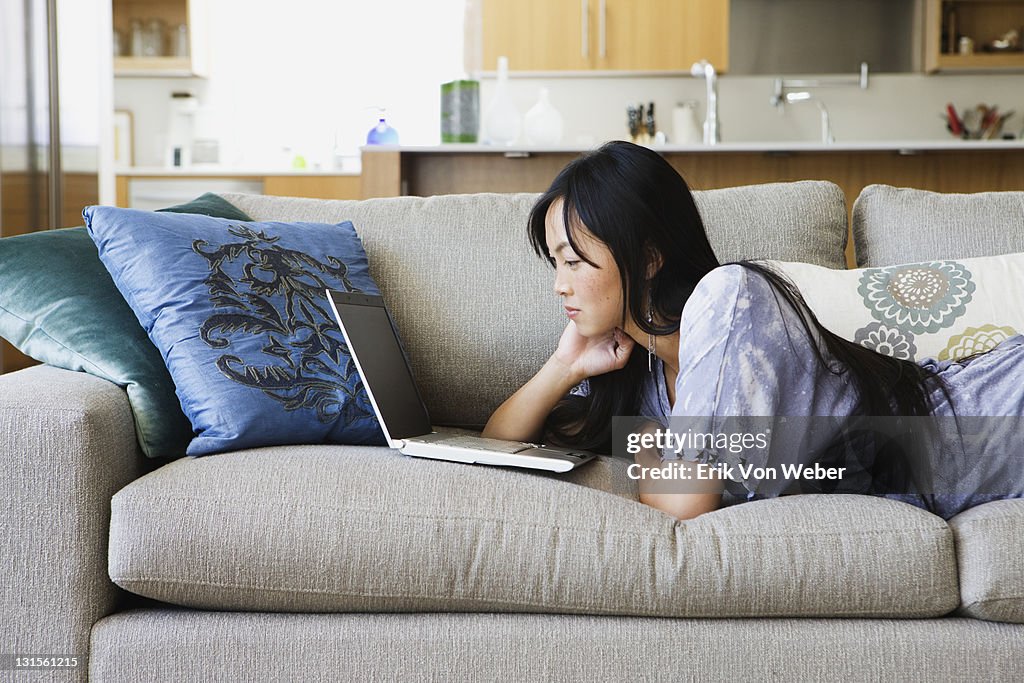 Asian woman on couch with laptop