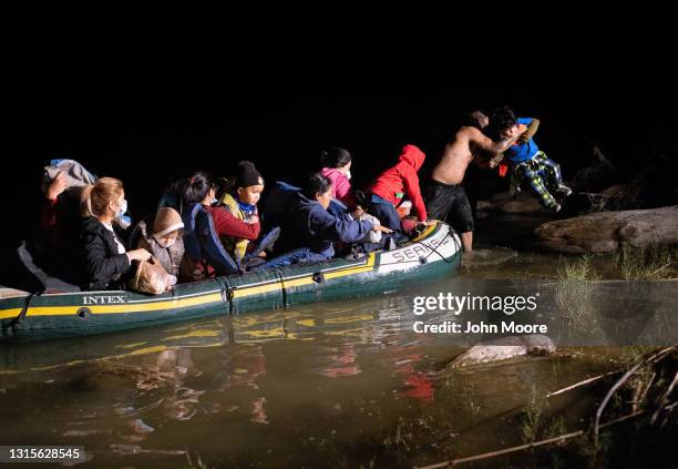 Smuggler lifts an immigrant child on to the bank of the Rio Grande after crossing the U.S.-Mexico border early on April 30, 2021 in Roma, Texas. A...