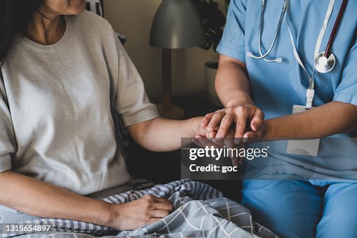 Close-up of a female nurse holding hands for reassuring her female patient on bed. Close-up of a female nurse holding hands for reassuring her female patient on bed.