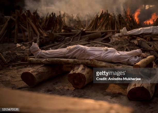 The body of a patient in a shroud who died of COVID-19 is kept on a funeral pyre before last rites are performed in a crematorium on May 01, 2021 in...