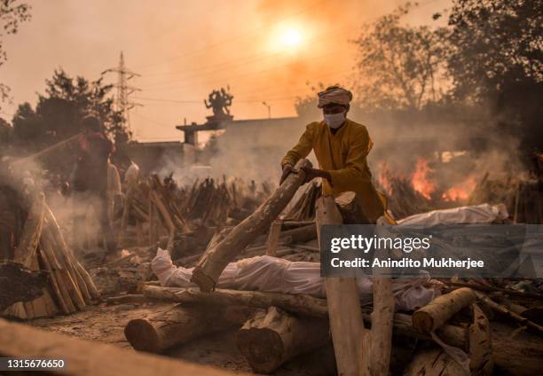 Priest who works at a crematorium performs the last rites of a patient who died of COVID-19 amid burning funeral pyres on May 01, 2021 in New Delhi,...