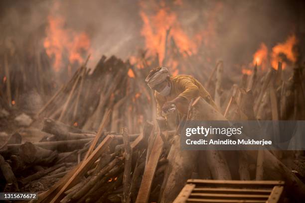 Priest who works at a crematorium performs the last rites of a patient who died of COVID-19 amid burning funeral pyres on May 01, 2021 in New Delhi,...